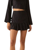 Paula Fashion House black linen mini skirt with high waist and ruffle hem, worn by a model.