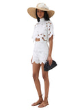 Paula Fashion House white floral cutwork high-waist shorts with scalloped hem, paired with a white crop top and straw hat.